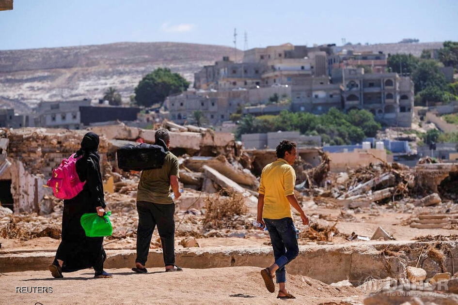 Libya_people-carrying-belongings-amidst-flood-debris