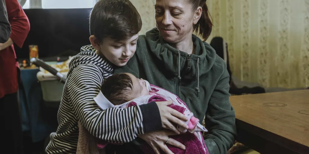 Katia holds her newborn baby, Malinka, while her son Oleksi, 8, looks on.