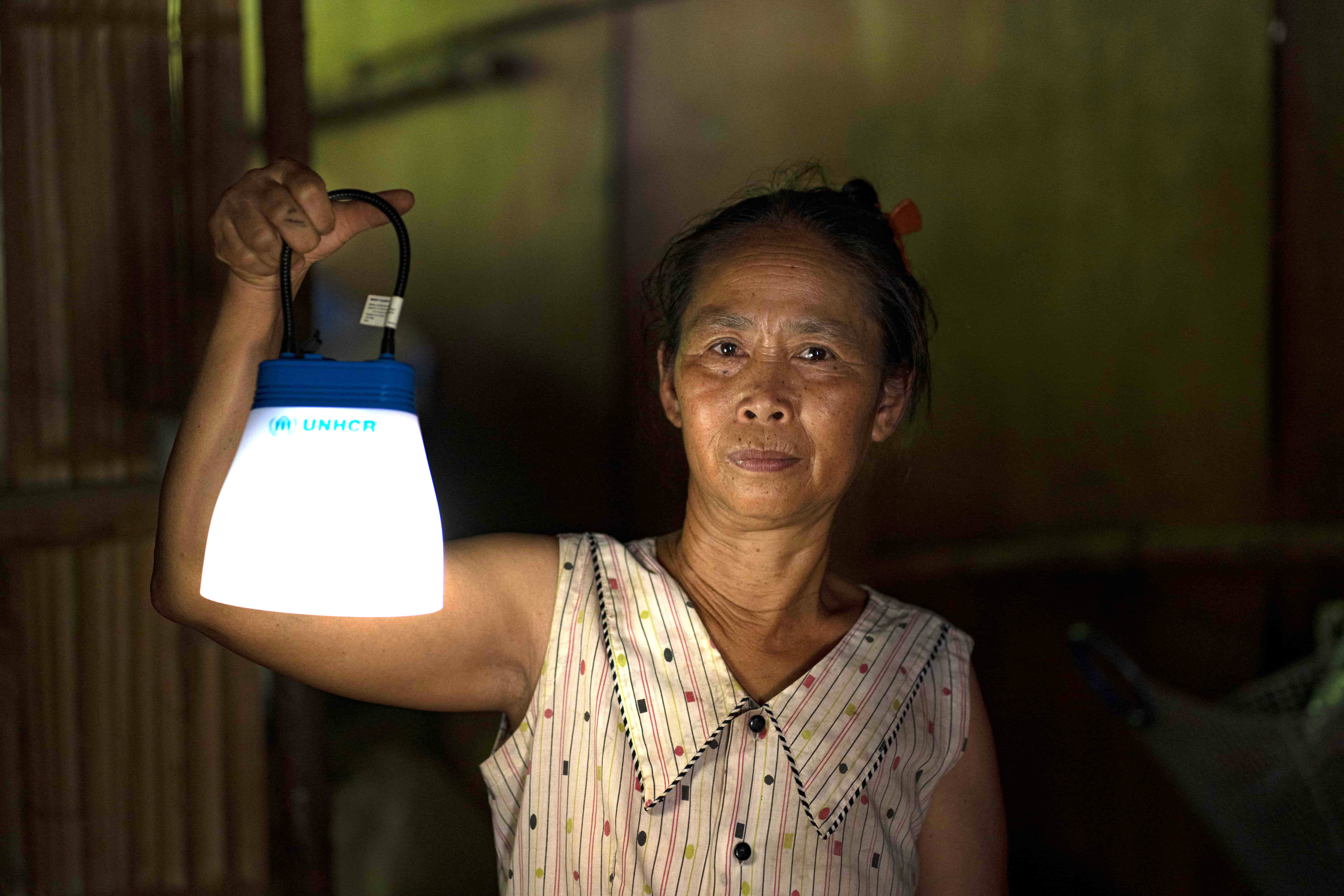 Myanmar Woman Holds Solar Lamp In Dark Shelter